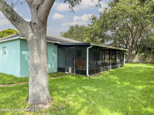 a view of a house with a yard and large tree