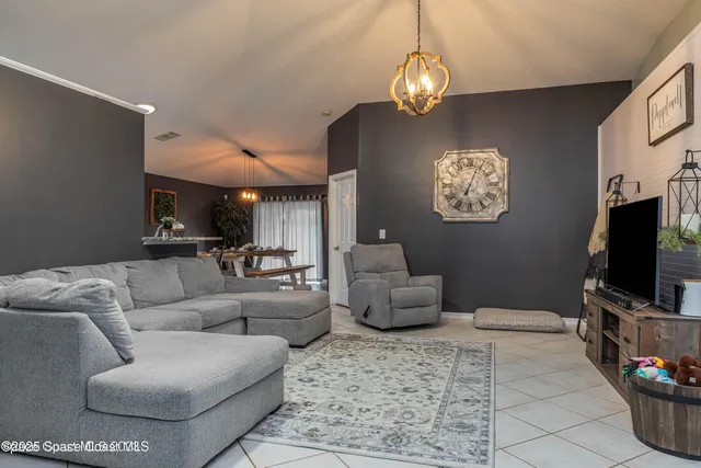 a living room with furniture a dining table and a chandelier