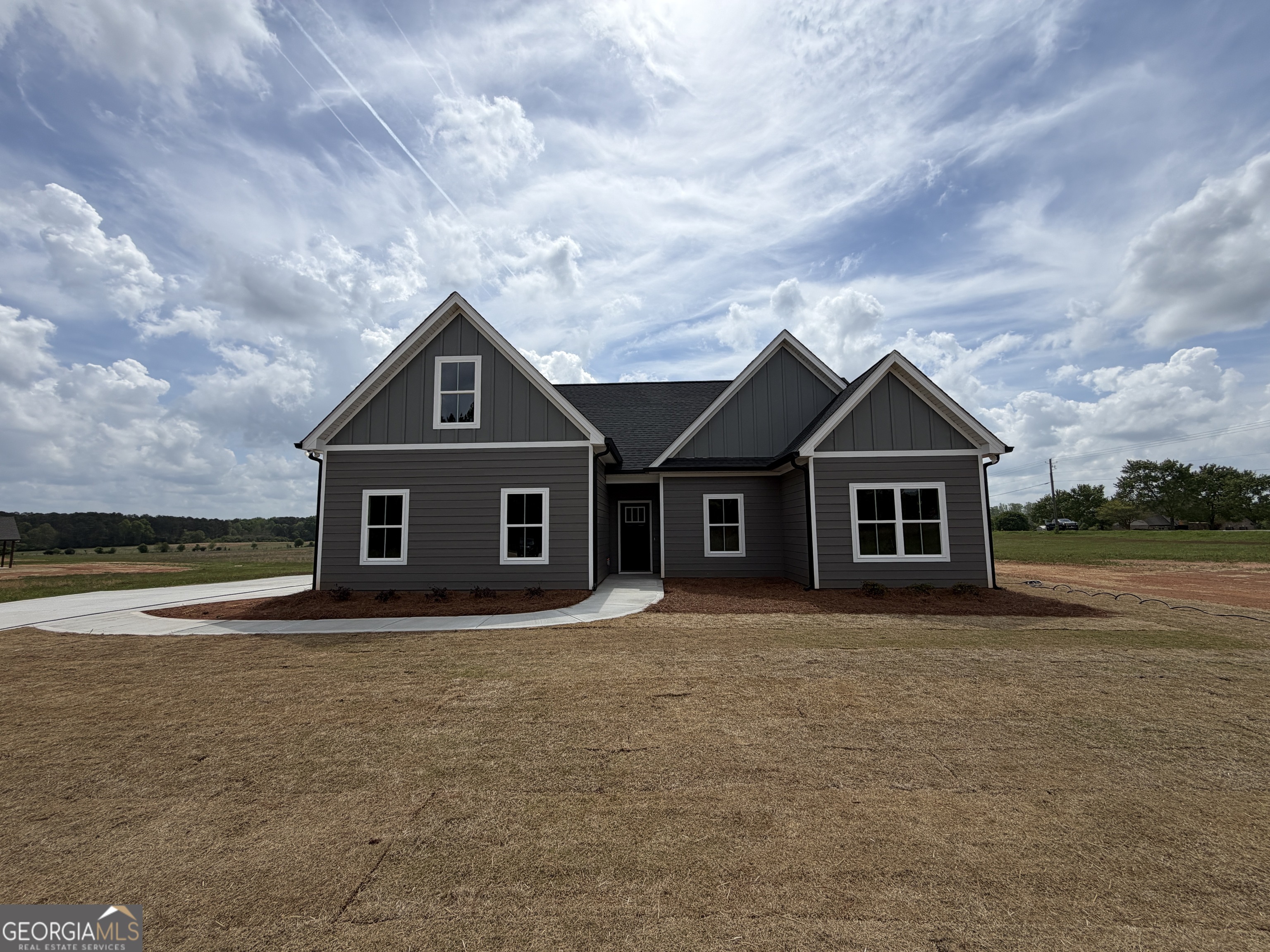 a front view of house with yard and trees in the background
