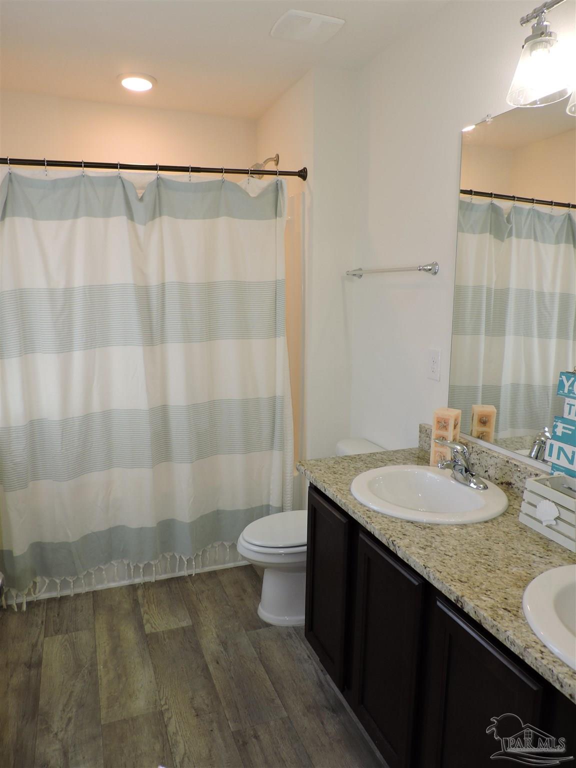 5840 Paddock Way Pensacola, FL 32526 - Photo 18 of 21 a bathroom with a granite countertop sink a toilet a mirror and shower
