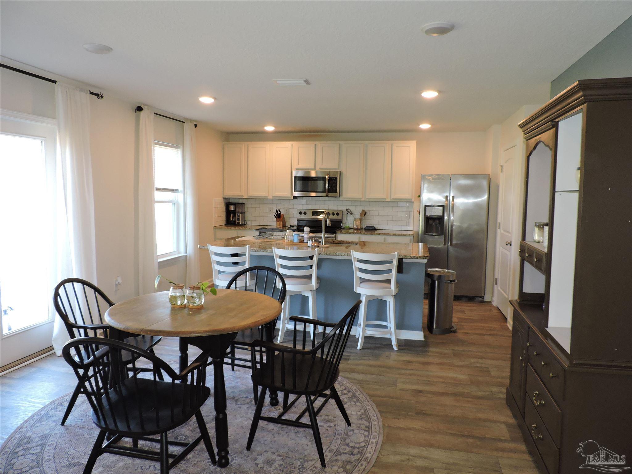 5840 Paddock Way Pensacola, FL 32526 - Photo 8 of 21 a view of a dining room with furniture a kitchen and chandelier
