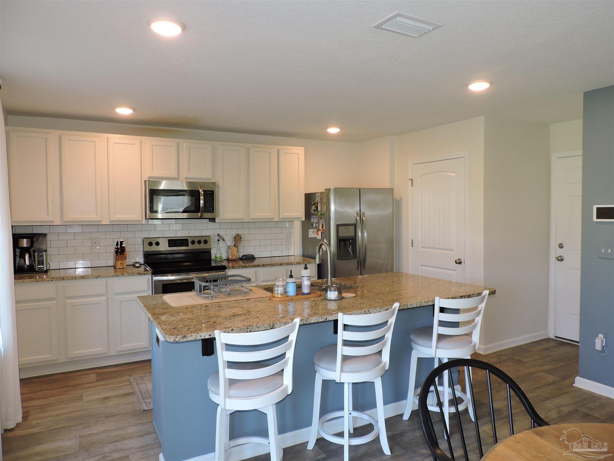 5840 Paddock Way Pensacola, FL 32526 - Photo 9 of 21 a kitchen with a refrigerator a stove a dining table and chairs