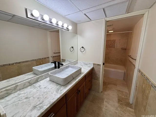 a bathroom with a granite countertop sink a mirror and shower