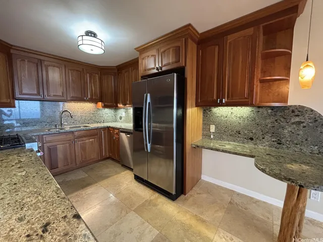 a kitchen with stainless steel appliances granite countertop a refrigerator a stove and a sink with wooden cabinets
