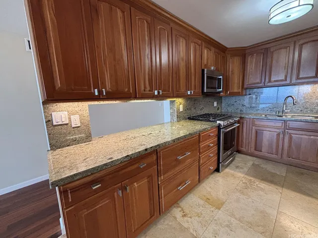 a kitchen with stainless steel appliances granite countertop wooden cabinets a stove top oven a sink and dishwasher