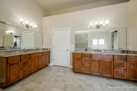 a bathroom with a granite countertop double vanity sink and a mirror