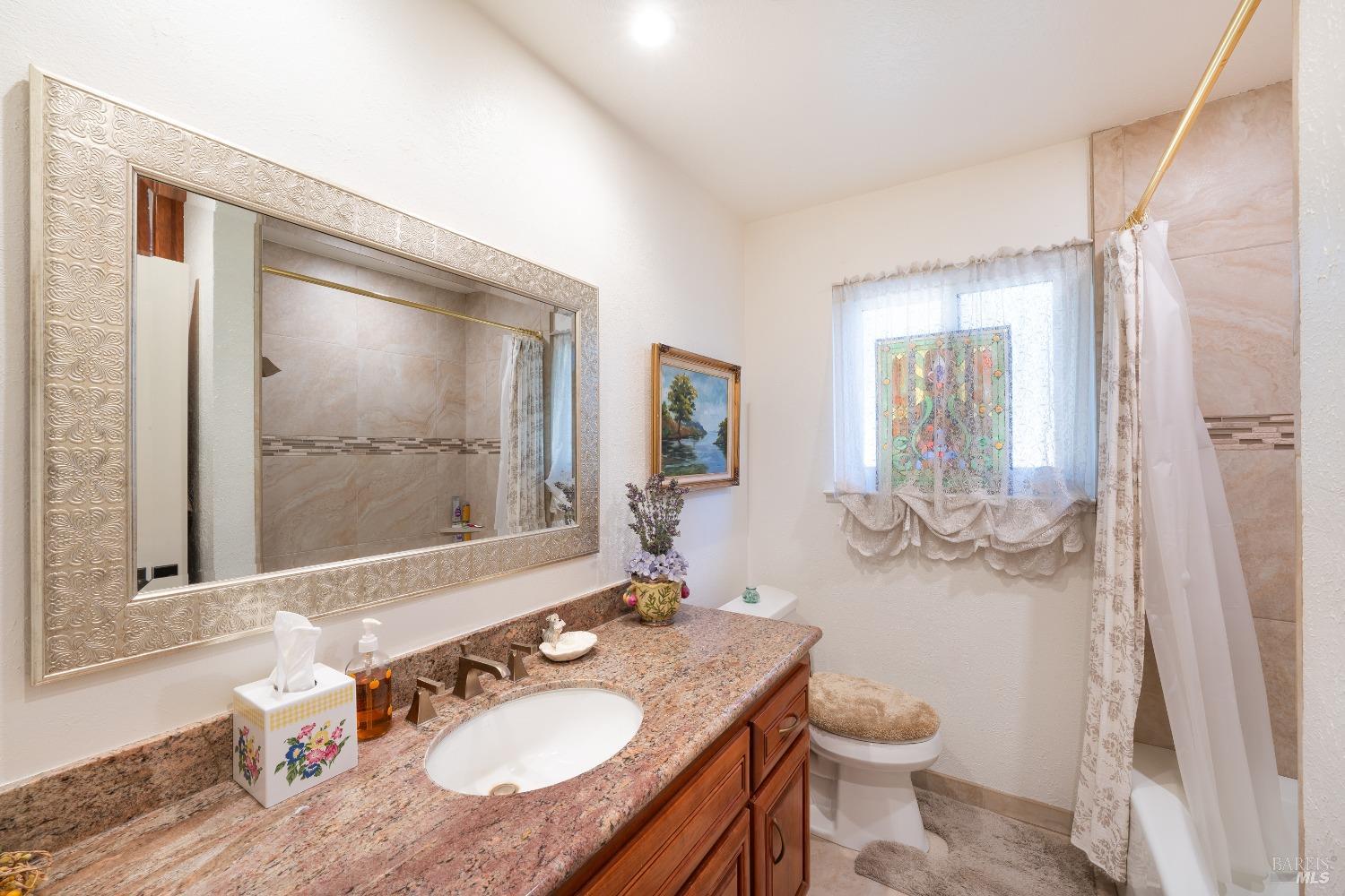 2208 Olivet Road Santa Rosa, CA 95401 - Photo 14 of 65 a bathroom with a granite countertop sink toilet and mirror