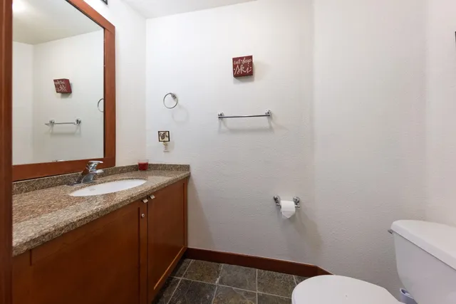 a bathroom with a granite countertop sink a toilet and a mirror