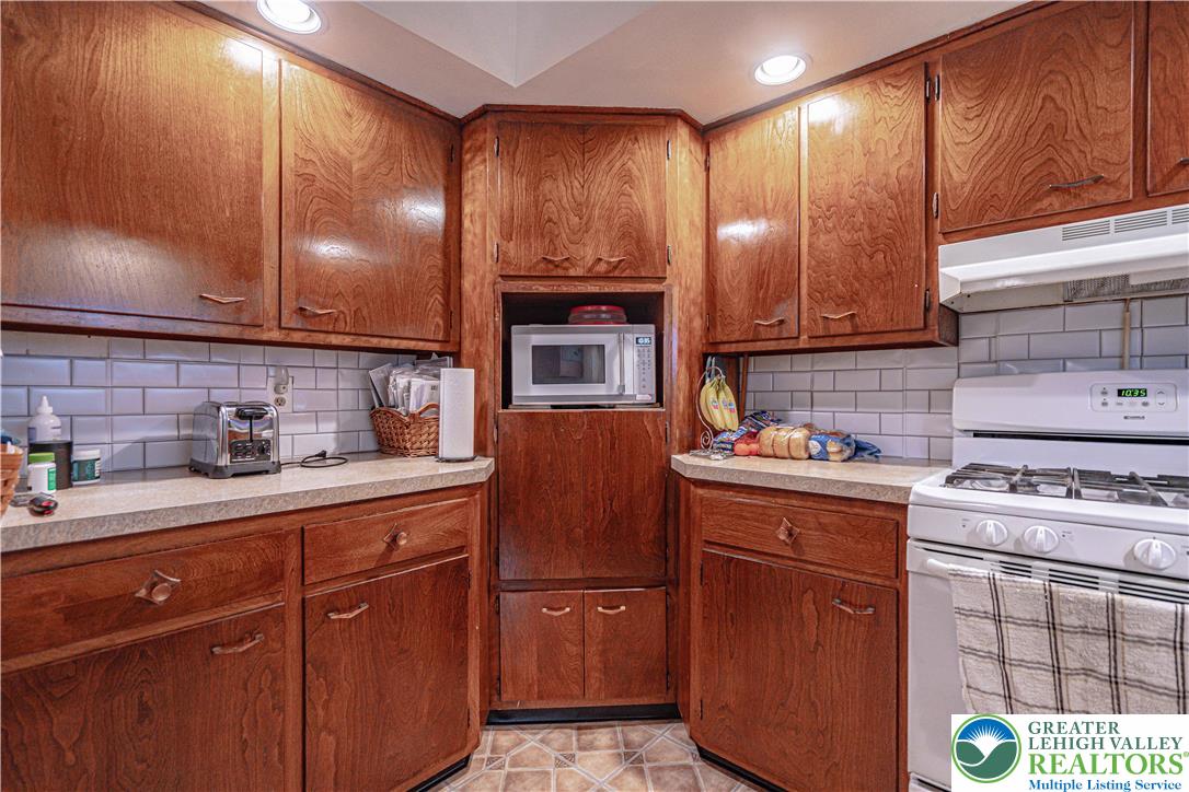 7562 Quarry Road Macungie, PA 18062 - Photo 16 of 35 a kitchen with kitchen island granite countertop wooden cabinets and white appliances
