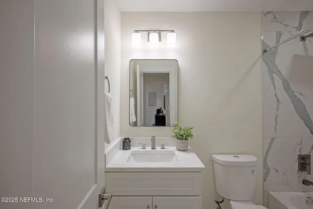 a view of a hallway with wooden floor and a bathroom