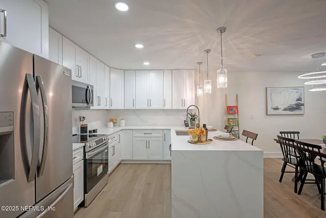 a kitchen with a refrigerator a stove a sink dishwasher with a dining table and chairs