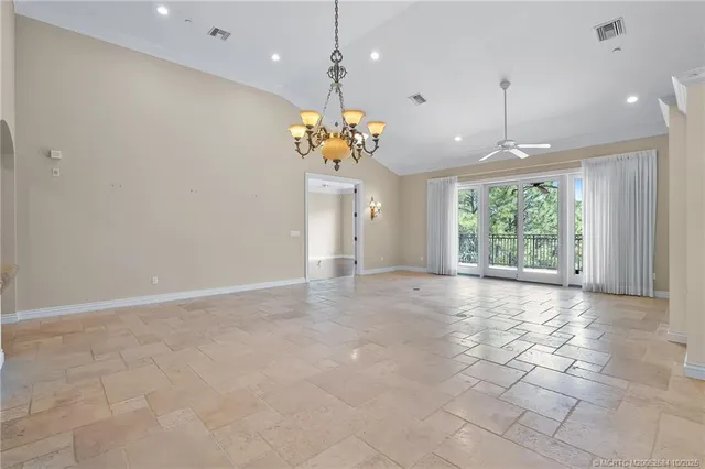 a view of an empty room with a windows and chandelier