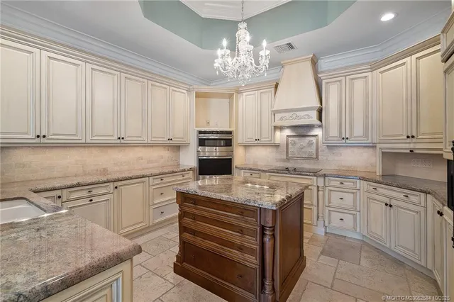 a kitchen with stainless steel appliances granite countertop a stove a sink and white cabinets