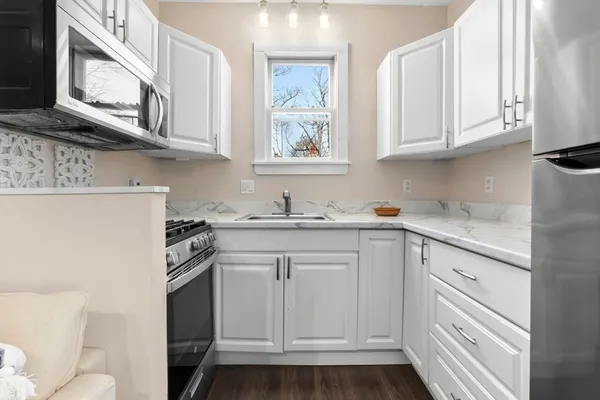 a kitchen with stainless steel appliances granite countertop white cabinets and sink