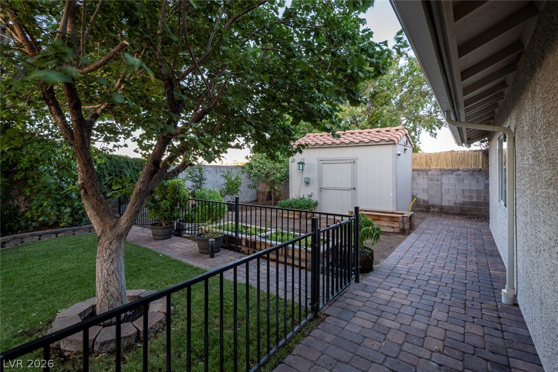 818 Manor Shores Road Henderson, NV 89002 - Photo 31 of 35 An inviting backyard oasis awaits with a lush lawn, paved walkway, and a practical storage shed.