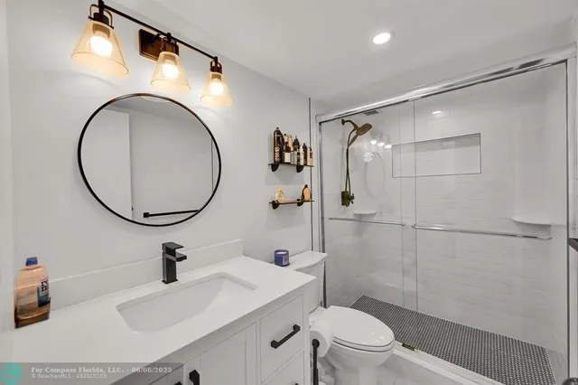 a bathroom with a sink a toilet a mirror and shower