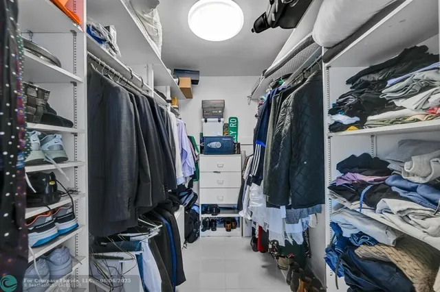 a view of walk in closet with clothes and shoes
