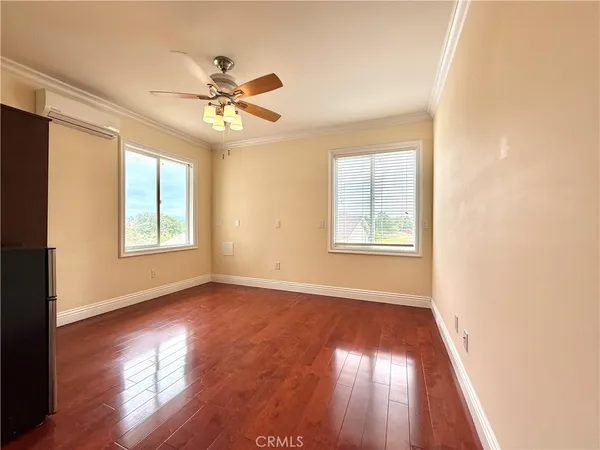 a view of empty room with wooden floor and fan