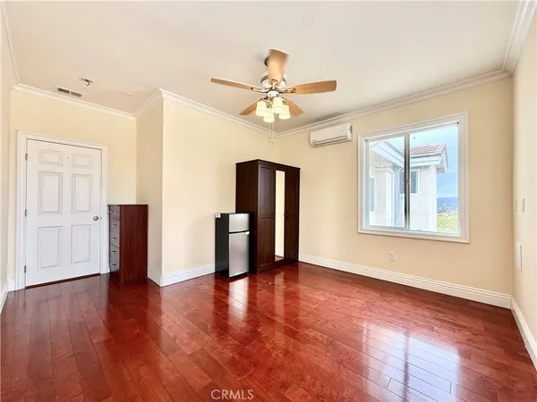 a view of an empty room with window and wooden floor