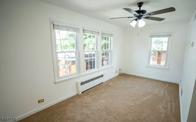 an empty room with chandelier fan and windows