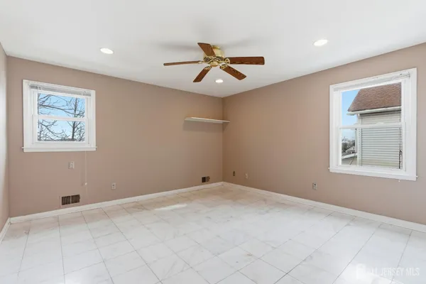 an empty room with windows and fan