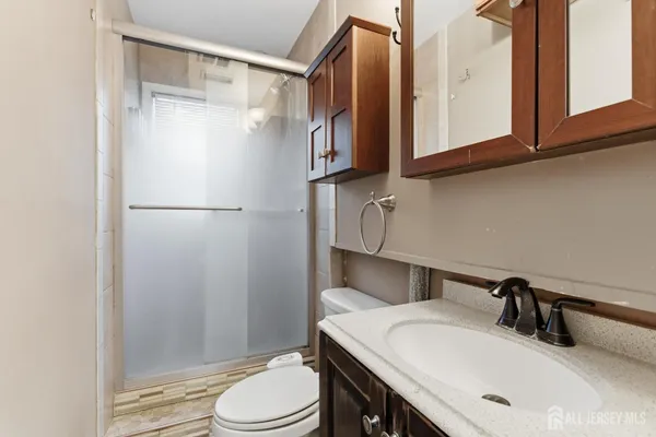 a bathroom with a sink vanity granite toilet and a mirror
