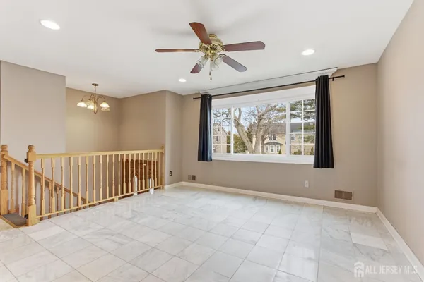 an empty room with ceiling fan and windows