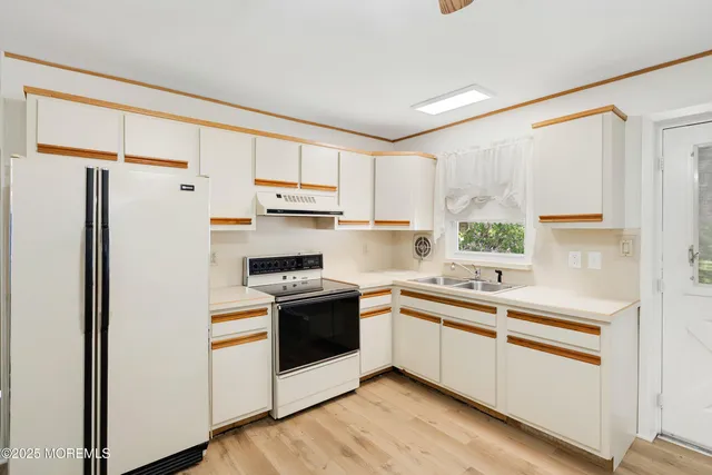 a kitchen with stainless steel appliances granite countertop a refrigerator a sink dishwasher a stove and white countertops with wooden floor