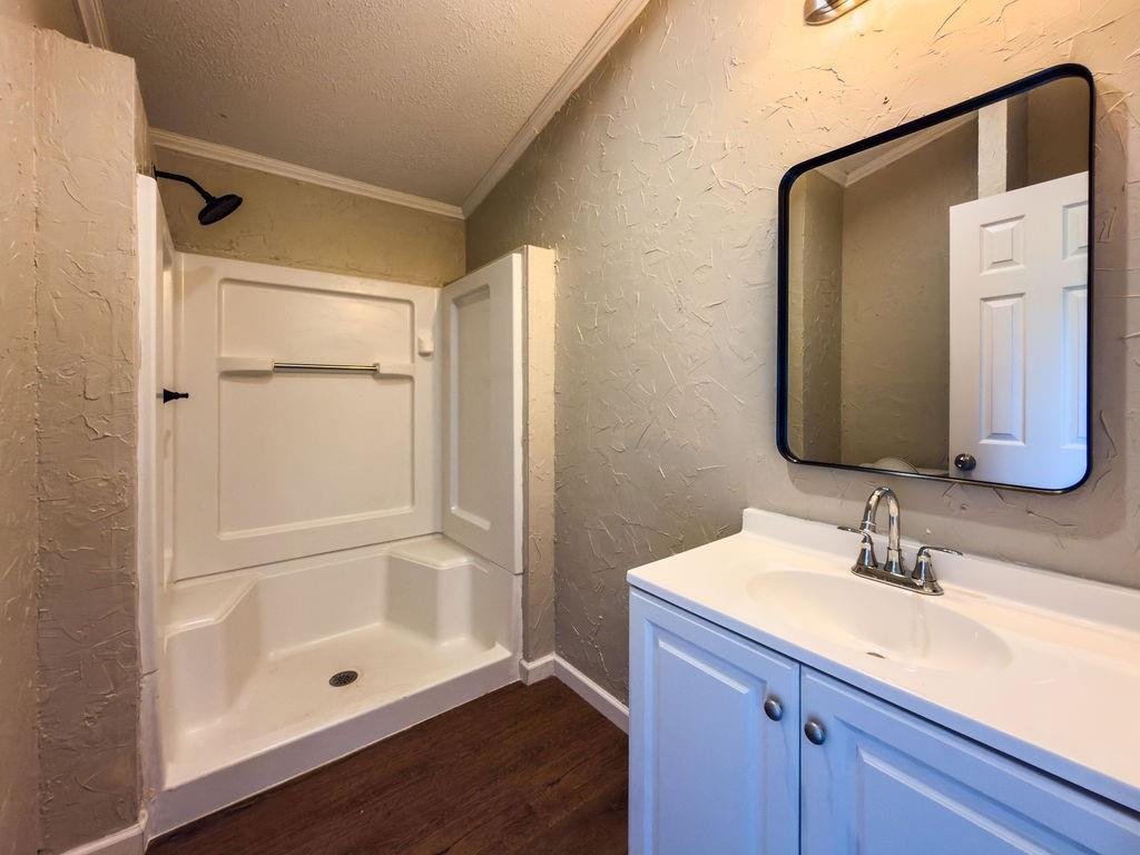 109 Brookshire Street Riesel, TX 76682 - Photo 11 of 18 Bathroom featuring a white shower stall with a black rain showerhead, a white vanity with integrated sink, chrome faucet, and a black-framed mirror