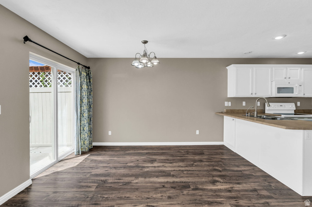 656 South 910 West, Unit 25 Pleasant Grove, UT 84062 - Photo 6 of 25 Open-concept kitchen and dining area featuring wood-finish flooring, white cabinetry, a kitchen island with sink, and a sliding glass door.