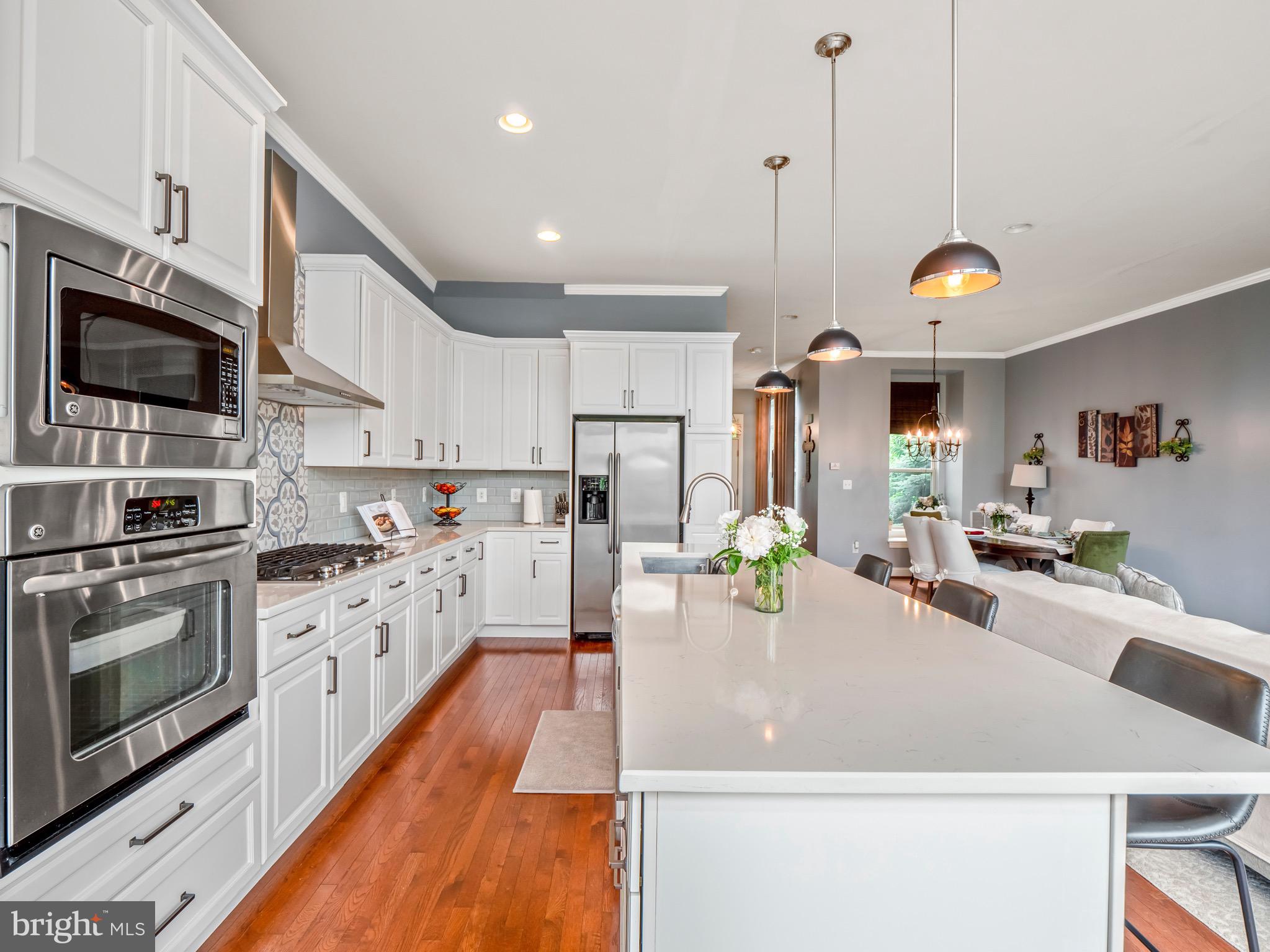 23366 Evening Primrose Square Brambleton, VA 20148 - Photo 4 of 28 a kitchen with stainless steel appliances kitchen island granite countertop a stove a sink and a microwave