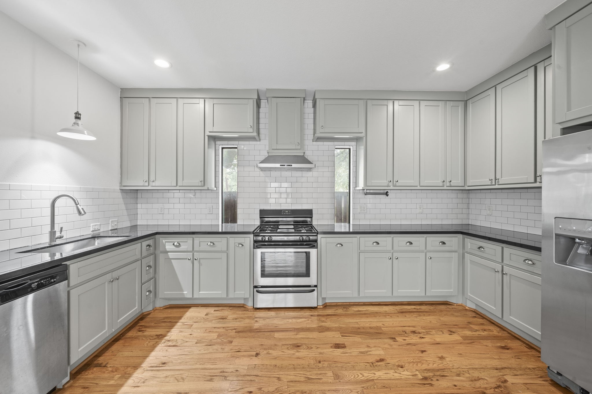 4734 Bell Street, Unit B Houston, TX 77023 - Photo 5 of 10 Large kitchen with extensive gray cabinetry, subway tile backsplash, stainless appliances, gas range, black countertops, and generous prep space.