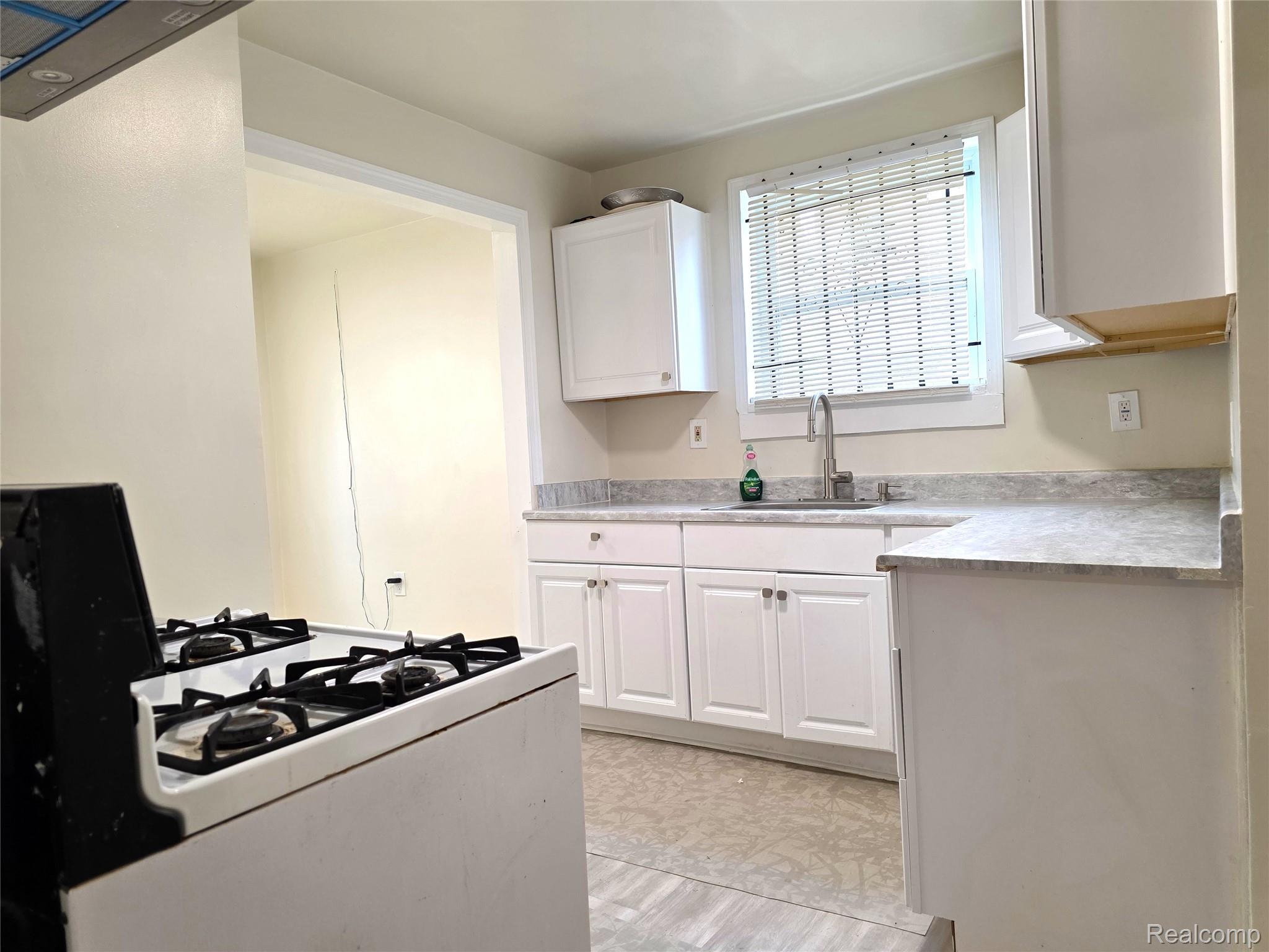 16814 Strathmoor Street Detroit, MI 48235 - Photo 8 of 31 Kitchen featuring white cabinetry, gray countertops, and a stainless steel sink with a gooseneck faucet