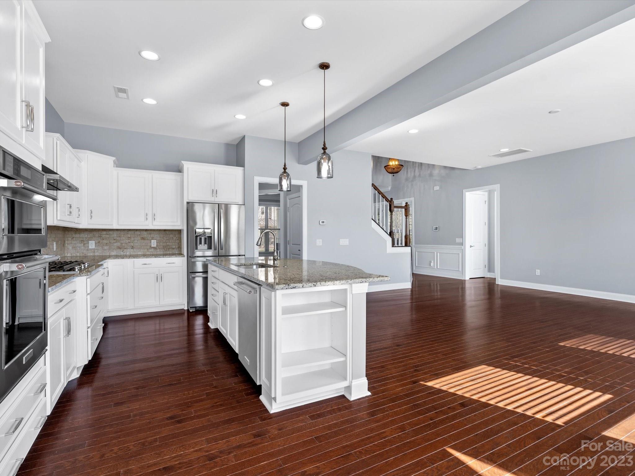7009 Fallondale Road Waxhaw, NC 28173 - Photo 17 of 47 a large kitchen with stainless steel appliances granite countertop a stove a sink dishwasher a refrigerator white cabinets and wooden floor next to a large window