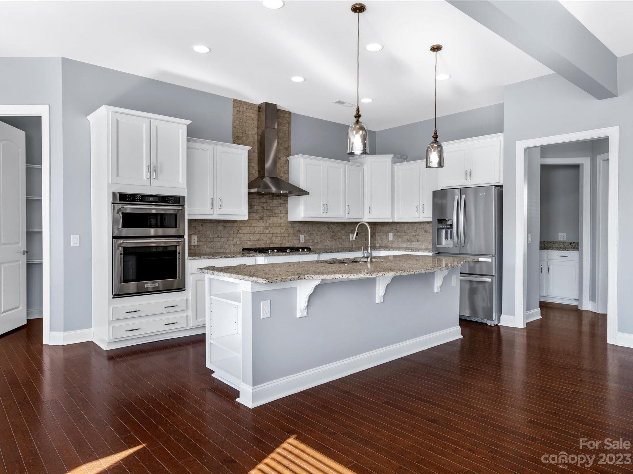 7009 Fallondale Road Waxhaw, NC 28173 - Photo 19 of 47 a kitchen with stainless steel appliances kitchen island a refrigerator a stove a oven and a wooden floor