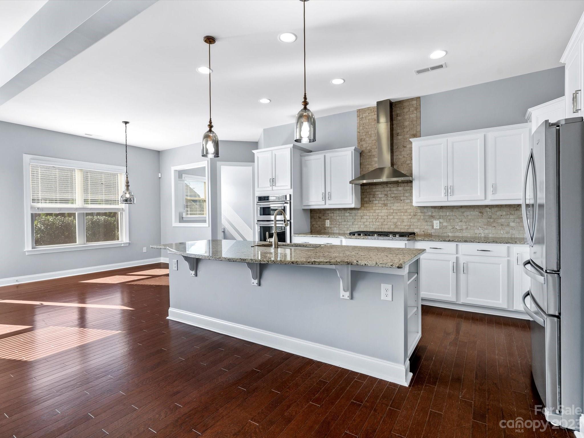 7009 Fallondale Road Waxhaw, NC 28173 - Photo 21 of 47 a large kitchen with granite countertop a stove a sink a center island and wooden floor