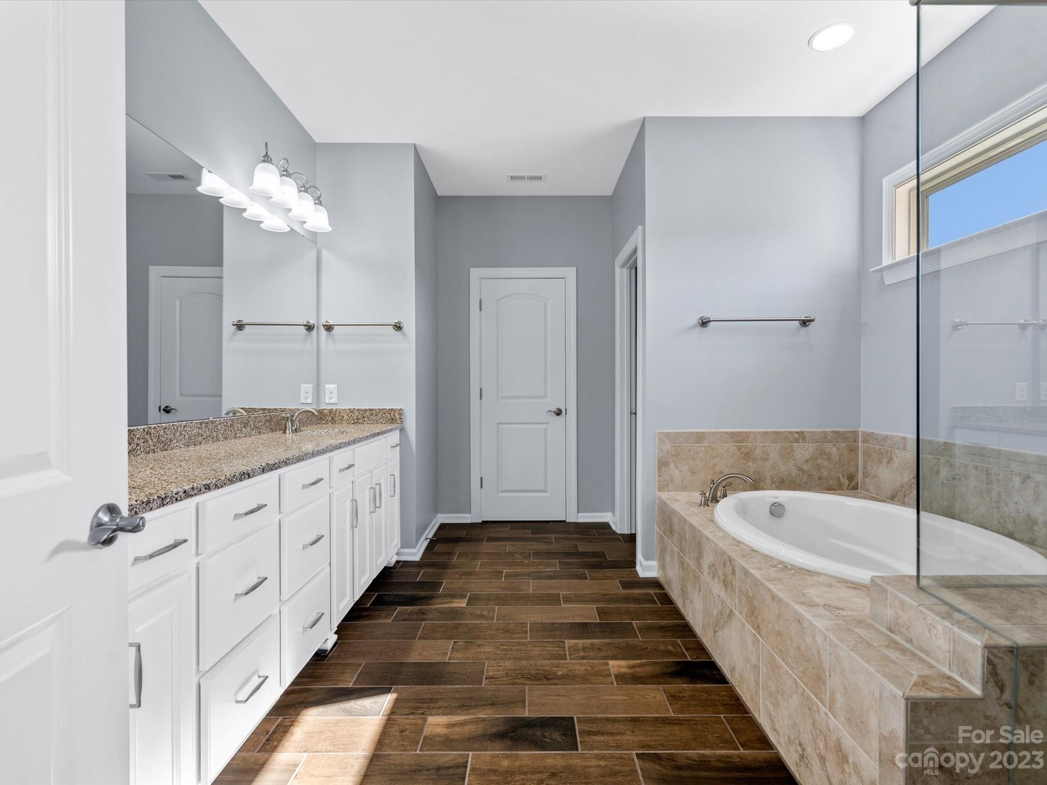 7009 Fallondale Road Waxhaw, NC 28173 - Photo 35 of 47 a bathroom with a tub a sink and a chandelier