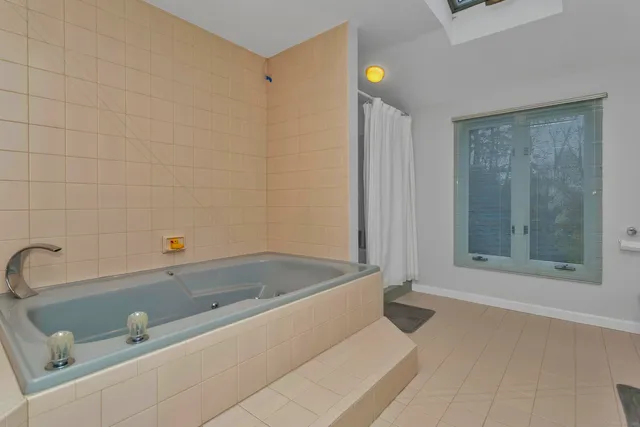 a bathroom with a tub a mirror and a shower