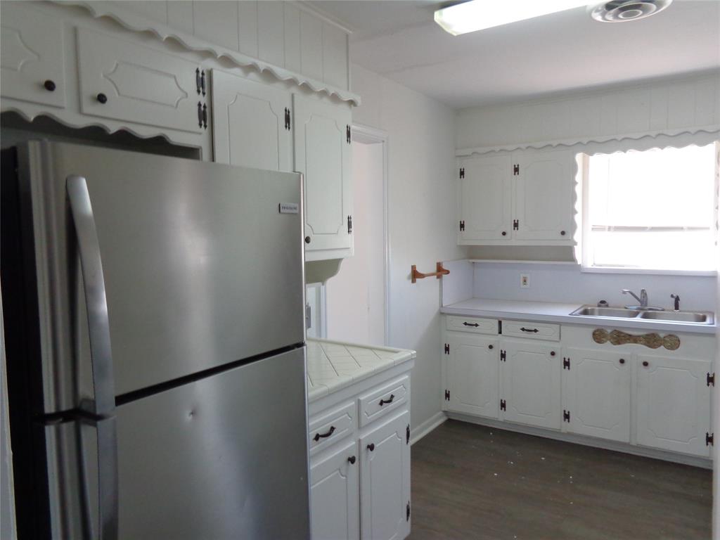 612 South Files Street Itasca, TX 76055 - Photo 28 of 30 Kitchen featuring freestanding refrigerator, white cabinetry, dark wood-style floors, and tile countertops