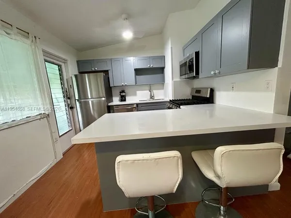 a kitchen with kitchen island a stove a sink a refrigerator dining table and chairs