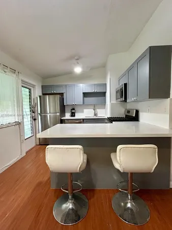 a kitchen with stainless steel appliances granite countertop a sink cabinets and wooden floor