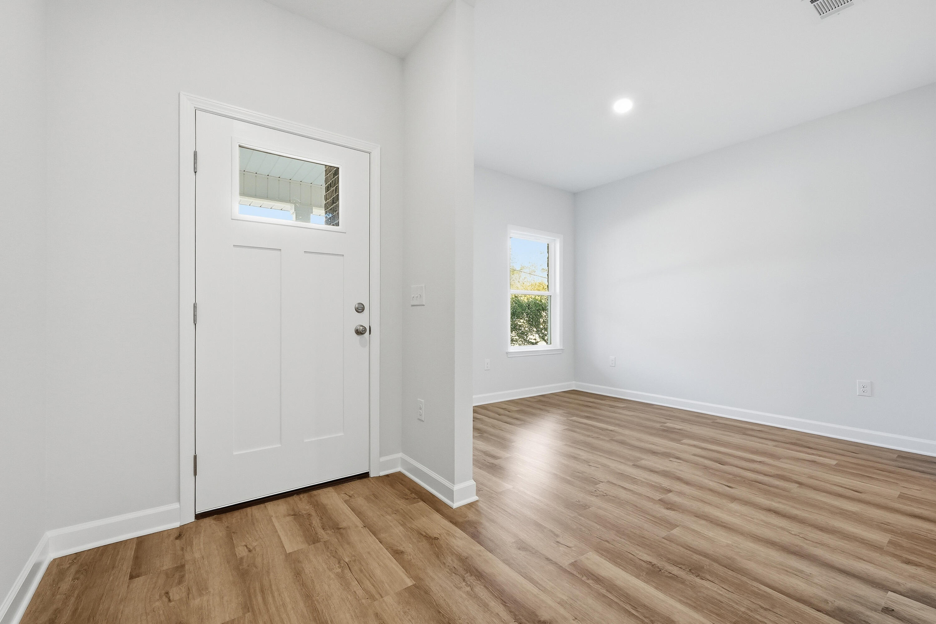 71 Spooner Street DeFuniak Springs, FL 32433 - Photo 3 of 22 an empty room with wooden floor and windows