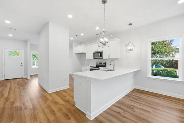 a view of a kitchen with a sink wooden floor and a chandelier