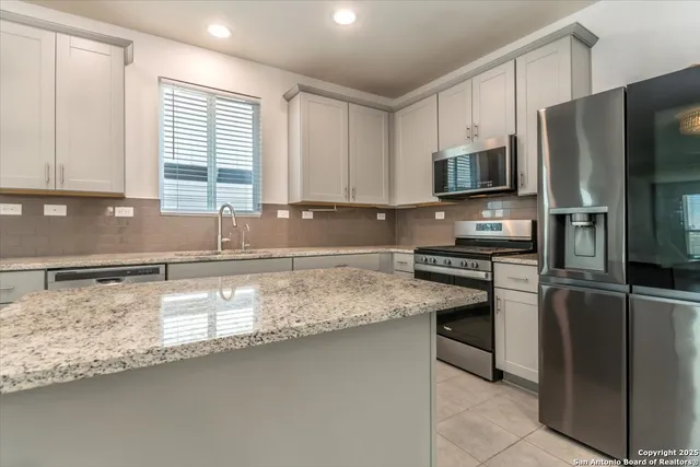 a kitchen with stainless steel appliances granite countertop a sink a stove top oven a refrigerator and a granite counter tops