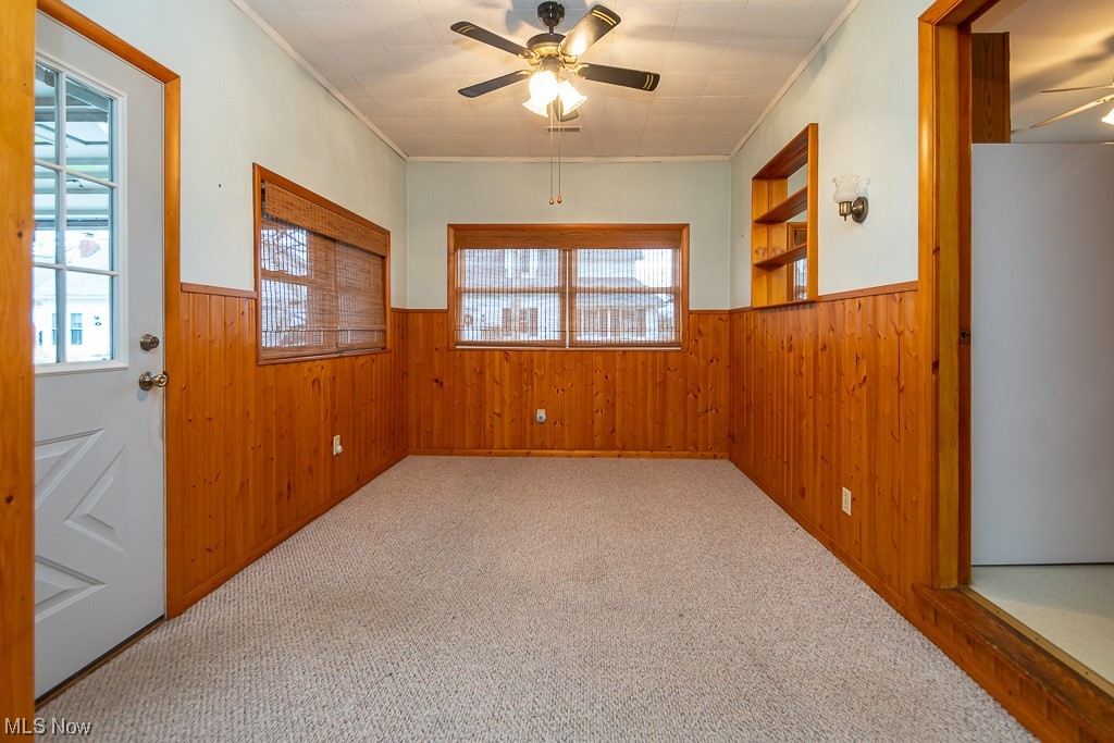 5 Pleasantview Vermilion, OH 44089 - Photo 14 of 37 Carpeted empty room with built in features, ceiling fan, wooden walls, and crown molding
