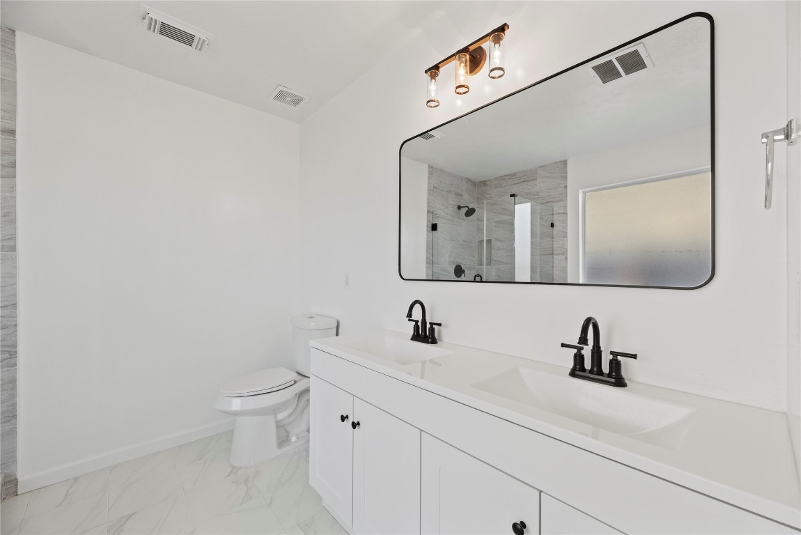 19910 Rustic Lake Lane Cypress, TX 77433 - Photo 9 of 21 This beautifully remodeled bathroom features a sleek double vanity with quartz countertops, modern black fixtures, and a large framed mirror paired with stylish statement lighting. Clean lines, neutral tones, and a spa-inspired walk-in shower with marble-look tile create a bright modern retreat.