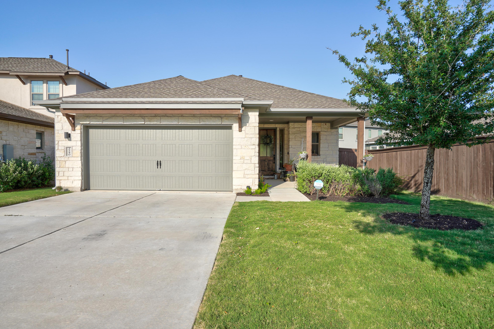 2240 Ringstaff Road Leander, TX 78641 - Photo 1 of 1 Stone and stucco exterior with a covered front porch featuring a dark wood entry door, a two-car garage, and a concrete driveway