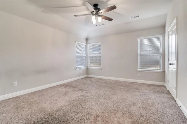 an empty room with windows and fan