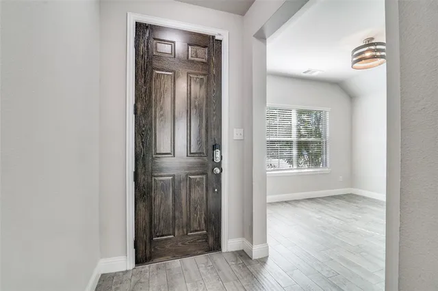 an empty room with wooden floor closet and windows