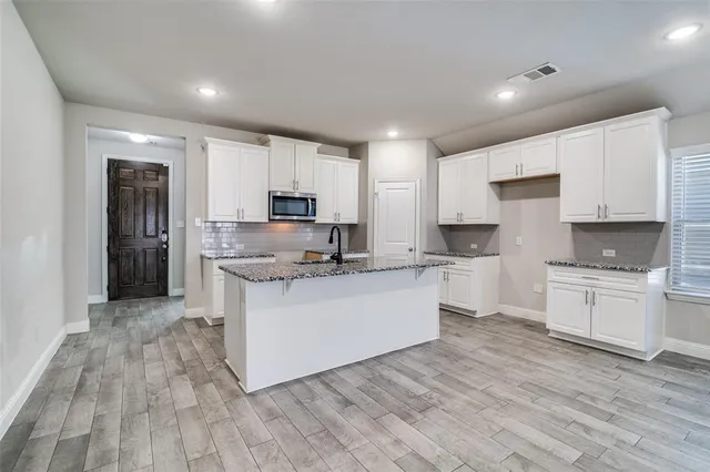 a large kitchen with cabinets wooden floor and stainless steel appliances